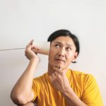 Difficult Conversation - Pensive ethnic man listening to answer in paper cup phone