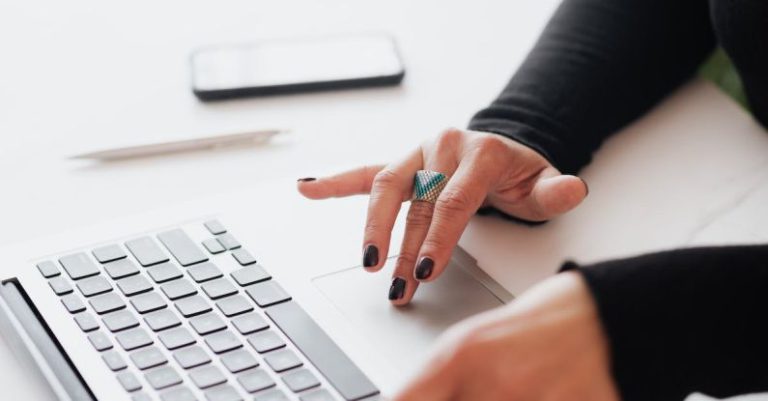 Career Enhancement - Crop female using touchpad on laptop in office
