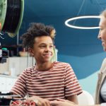 Future Workplace - Positive young male engineer sitting at table with woman and working together on project in light room