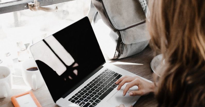 Freelancer Lifestyle - Close-up Photography of Woman Sitting Beside Table While Using Macbook