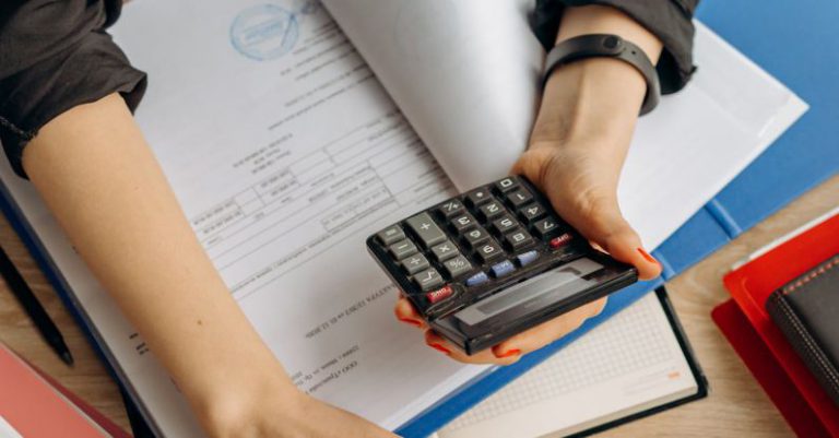 Tax Documents - Person Holding Black Calculator While Using Laptop