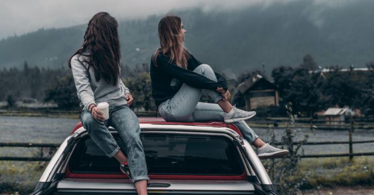 Vacation Concept - Two Women Sitting on Vehicle Roofs