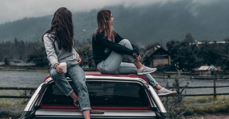 Vacation Concept - Two Women Sitting on Vehicle Roofs