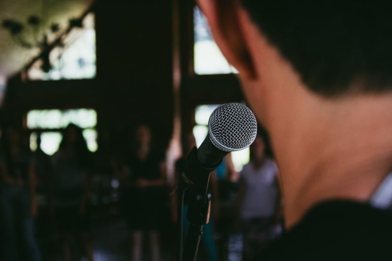 Public Speaking - man standing in front of microphone
