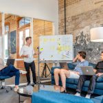 Career - three men sitting while using laptops and watching man beside whiteboard