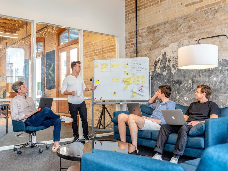 Career - three men sitting while using laptops and watching man beside whiteboard