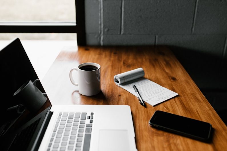 Career - MacBook Pro, white ceramic mug,and black smartphone on table