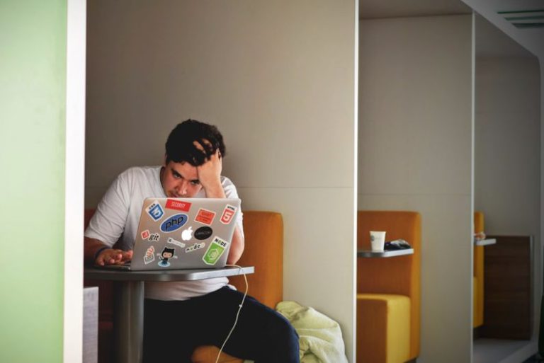 Stress - man wearing white top using MacBook