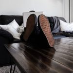 Relax Work - person sitting on sofa resting its feet on top of coffee table while using laptop