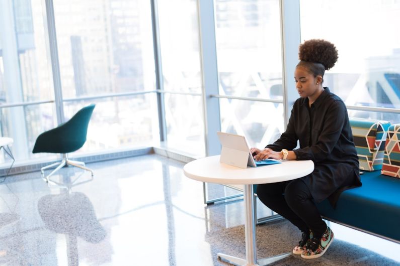 Networking Work - woman sits of sofa while using tablet computer