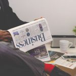 Financial Stability - person sitting near table holding newspaper