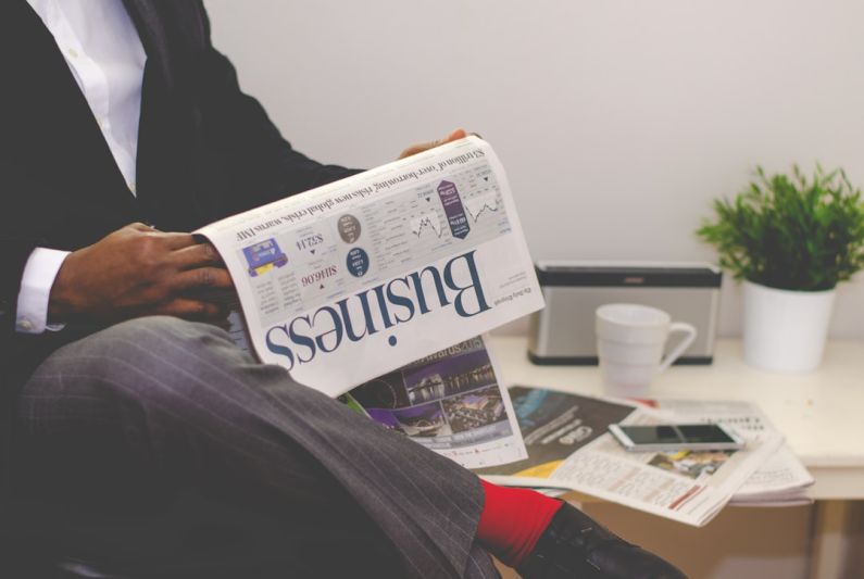 Financial Stability - person sitting near table holding newspaper