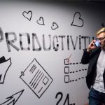 Entrepreneurship - man holding smartphone looking at productivity wall decor