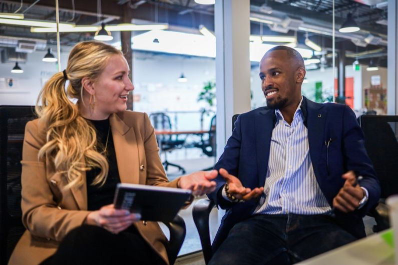 Entrepreneurship - man in black suit jacket sitting beside woman in brown blazer