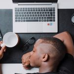 Procrastination - a man sitting at a desk with a laptop and headphones