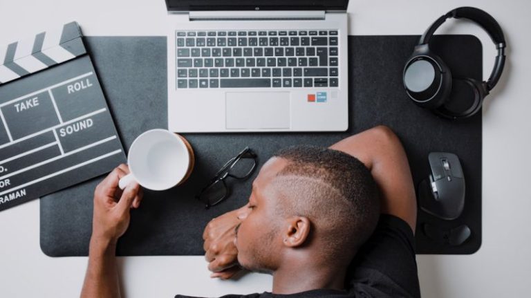 Procrastination - a man sitting at a desk with a laptop and headphones