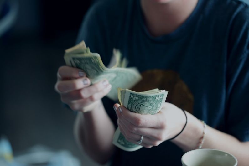 Personal Finance - focus photography of person counting dollar banknotes